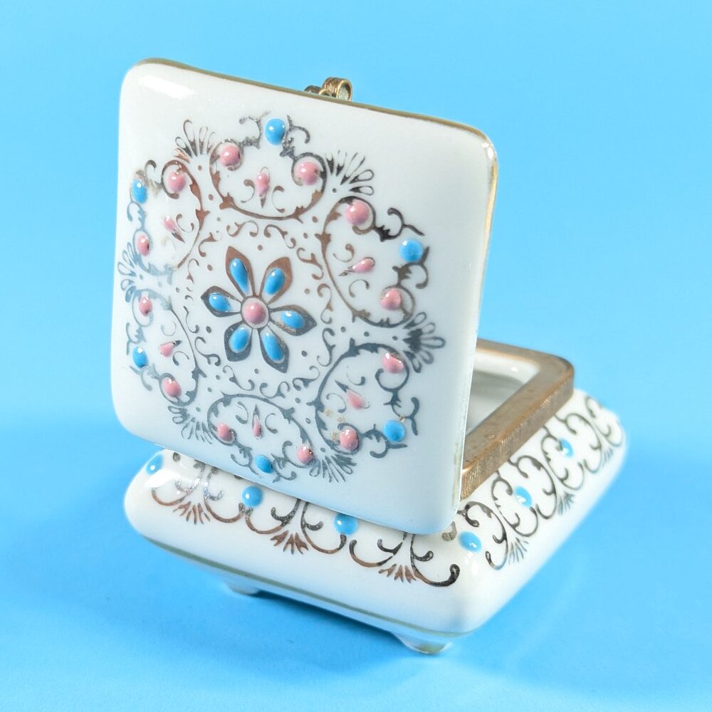 White porcelain lidded trinket box with silver, blue and pink pattern